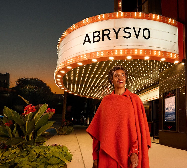 Adult beneath ABRYSVO® marquee, representing learning about RSV prevention.
