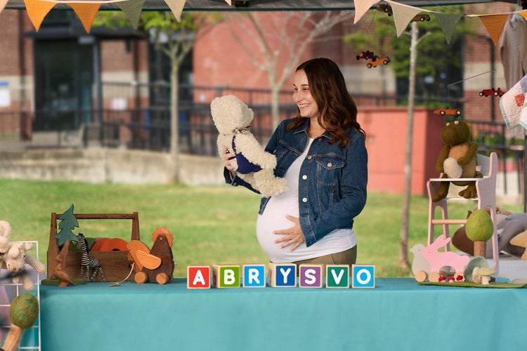 Scène de grossesse avec des articles de chambre de bébé et l’image de marque ABRYSVOMD, mettant en valeur la vaccination maternelle pour aider à protéger les nourrissons contre le VRS.