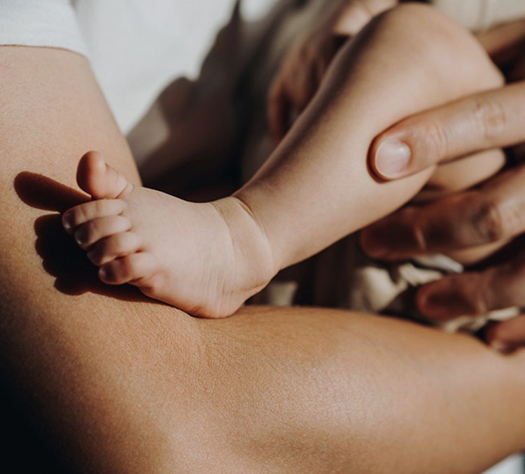 Bébé tenu dans les bras d’un adulte, illustrant comment la vaccination maternelle contre le VRS peut contribuer à protéger les nourrissons après la naissance.