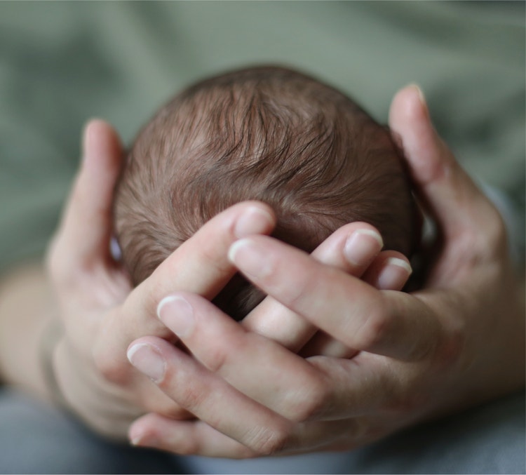 Newborn infant cradled in caring hands, representing RSV protection in early infancy.